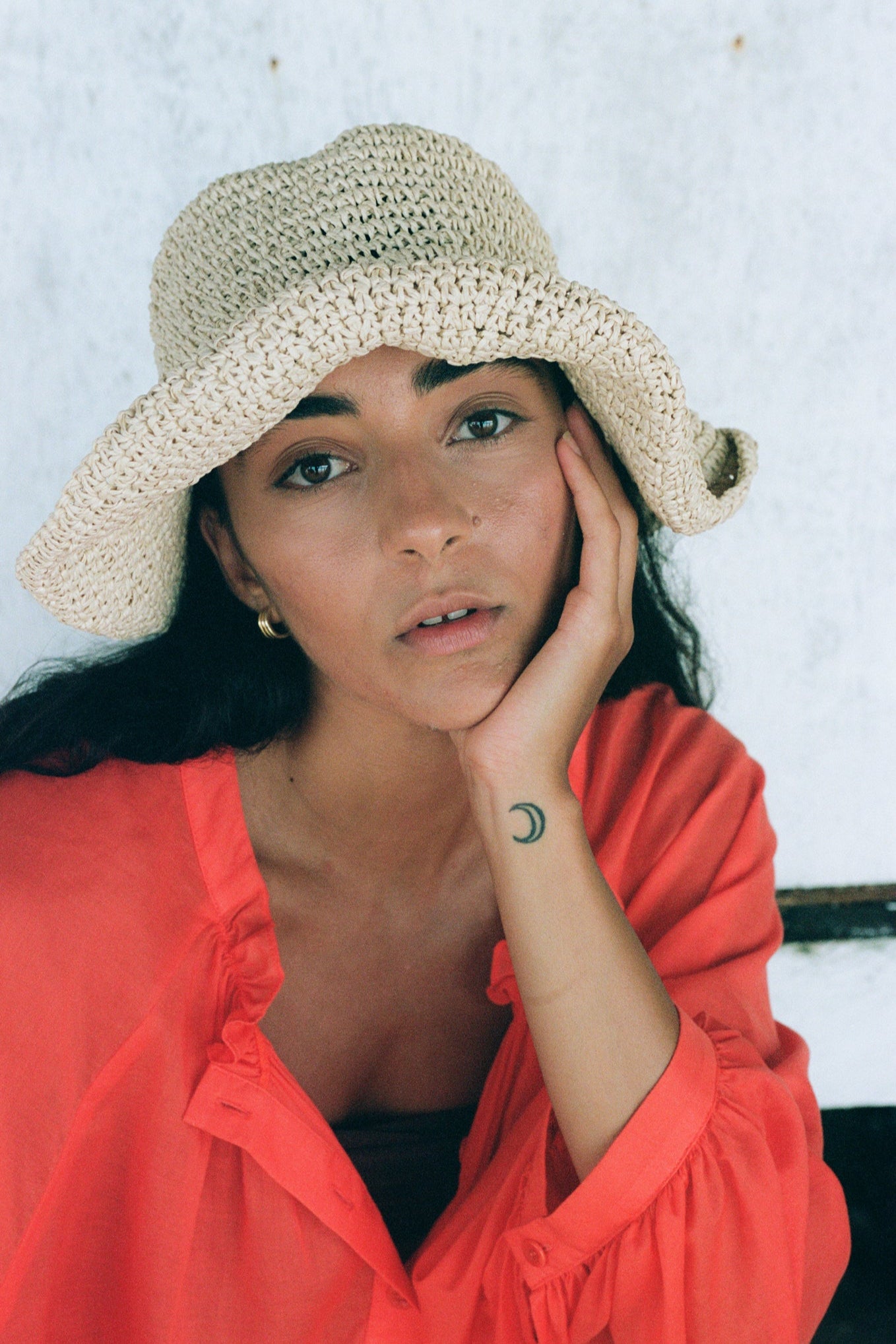 LILLY PILLY woman wearing a spritz Thalia cotton voile shirt wearing a beige crochet hat and red top against a white wall