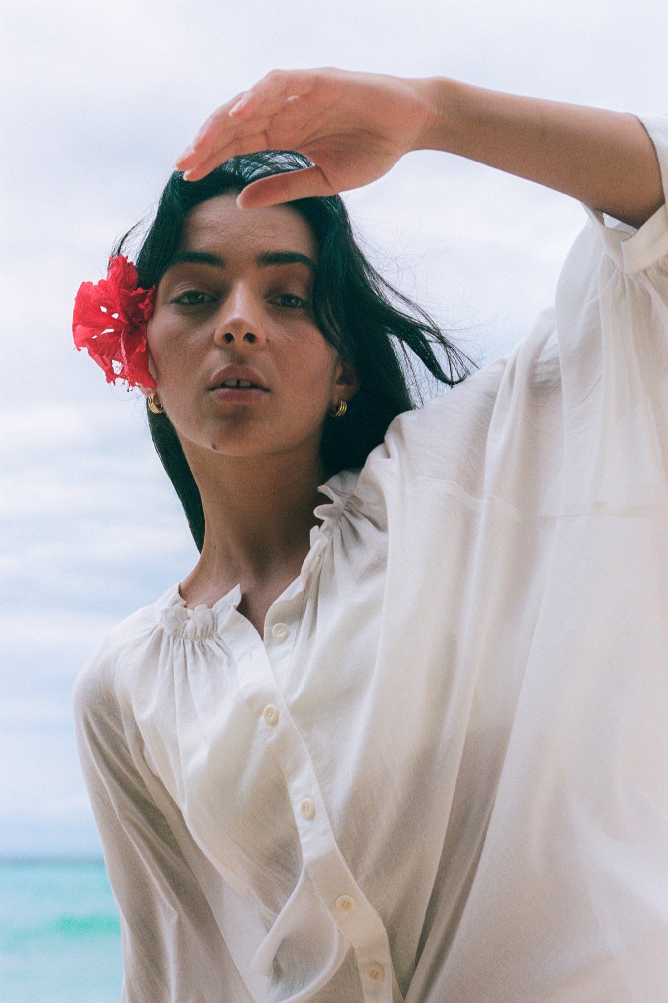 Close up of LILLY PILLY woman wearing a ivory Thalia cotton voile shirt blouse with a flower in her hair