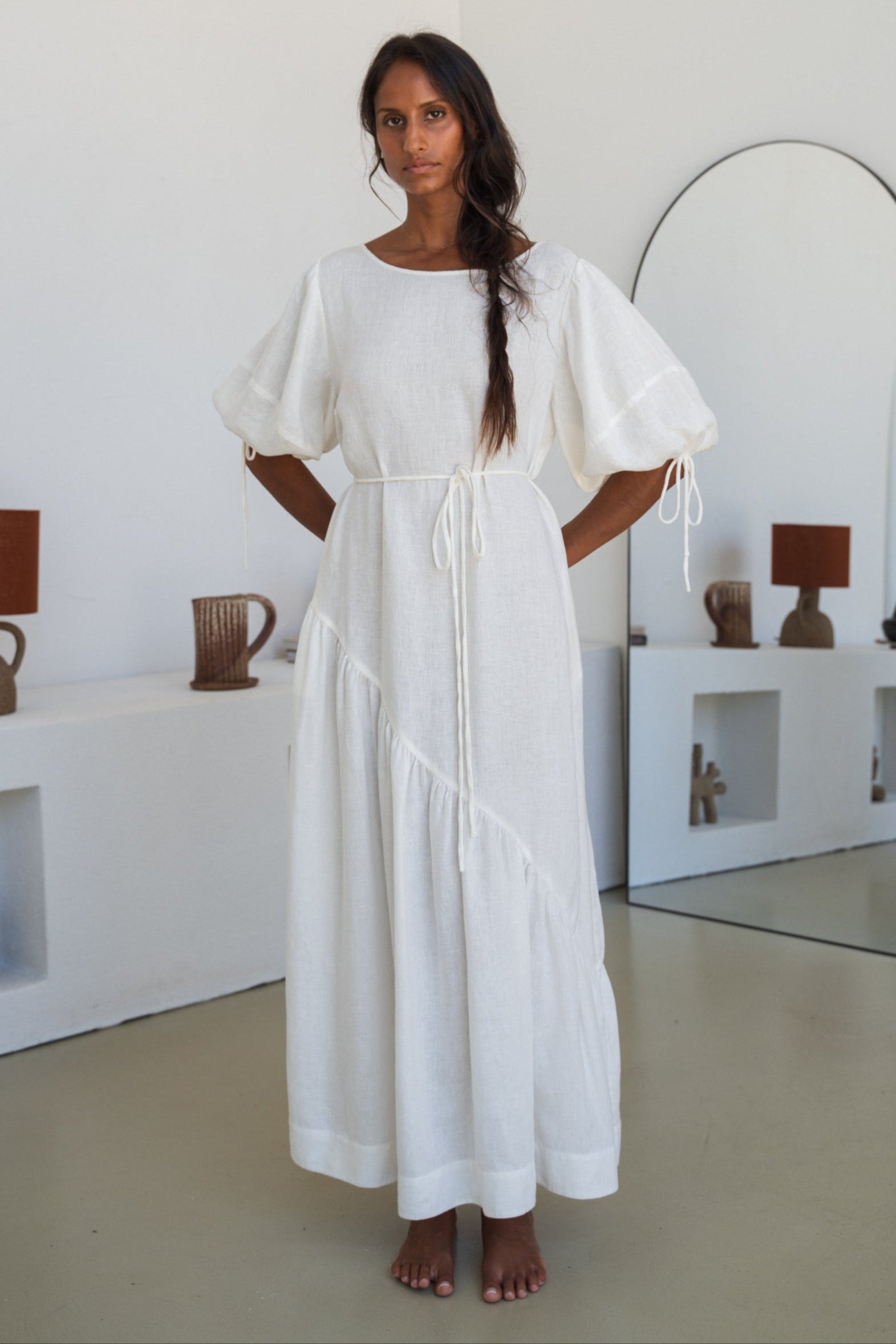 LILLY PILLY woman wearing Charlotte linen dress in Ivory standing in front of a mirror