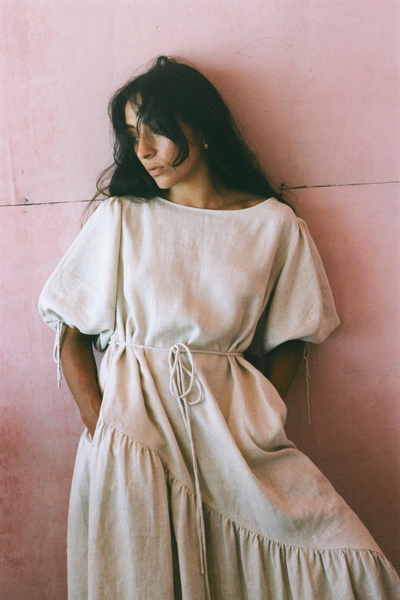 LILLY PILLY woman in an oatmeal Charlotte dress standing against a pink wall