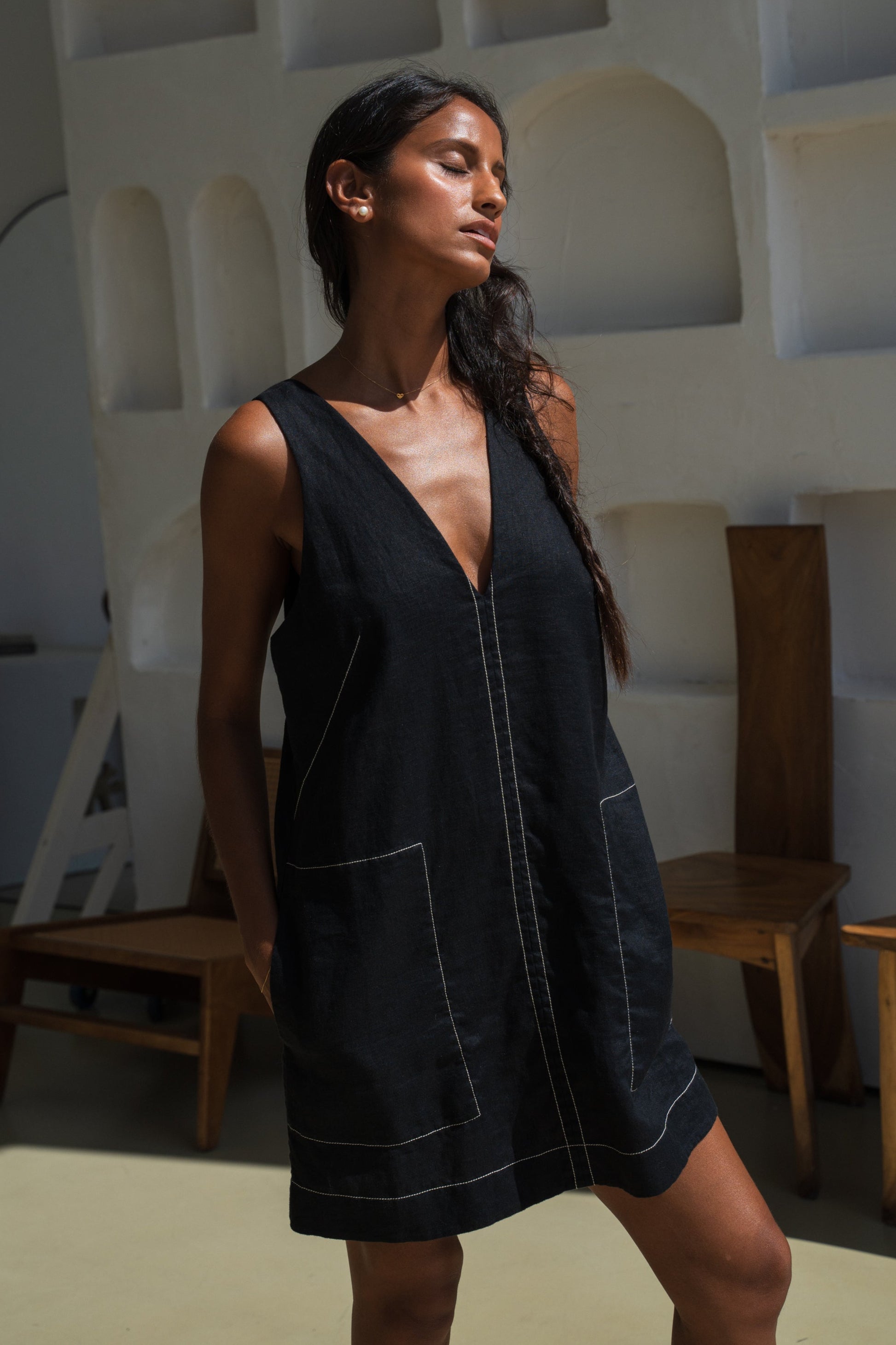LILLY PILLY woman in an black Isla linen dress with white stitching in an indoor setting