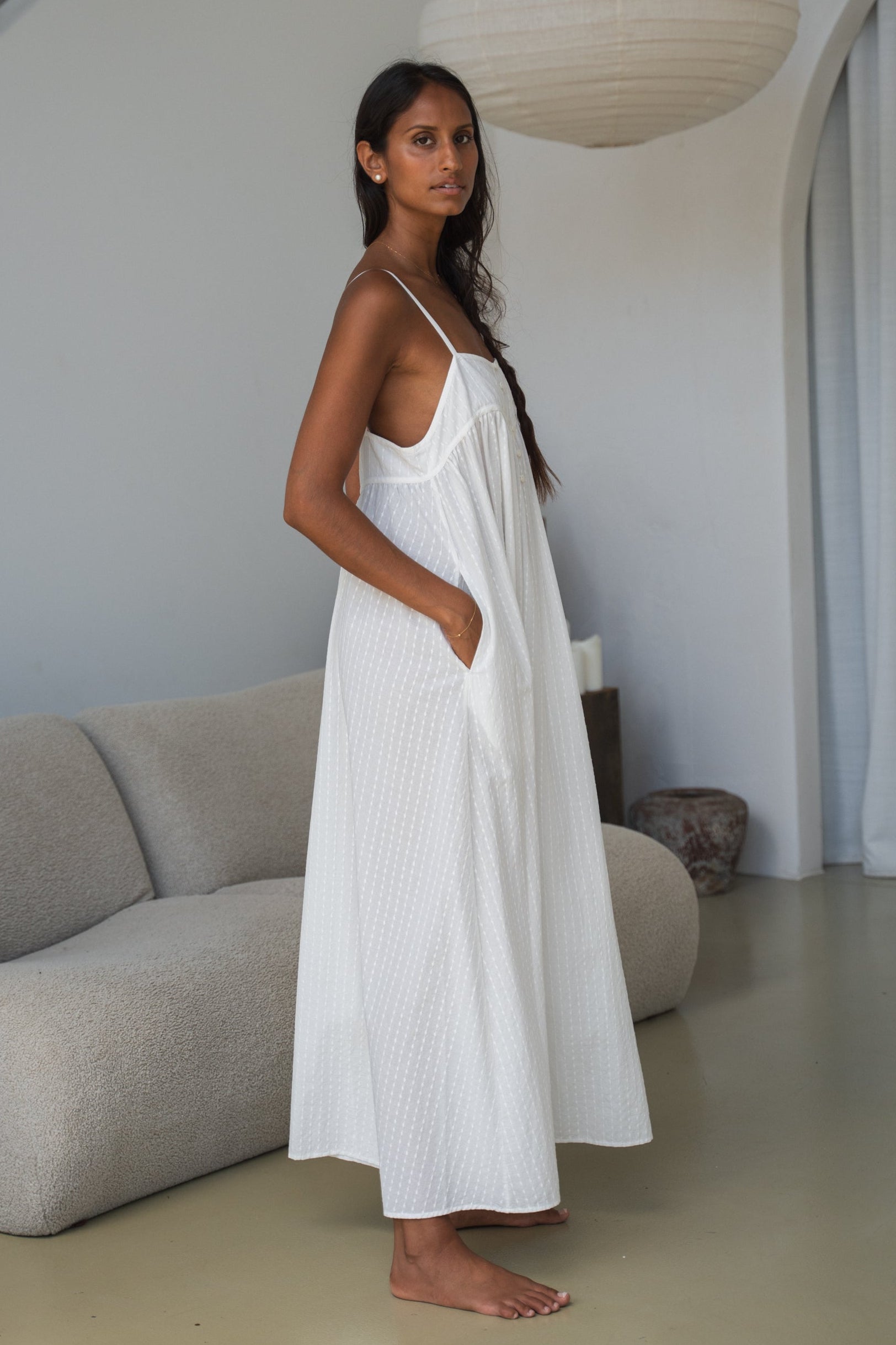 Woman wearing a white dress standing in a modern living room.