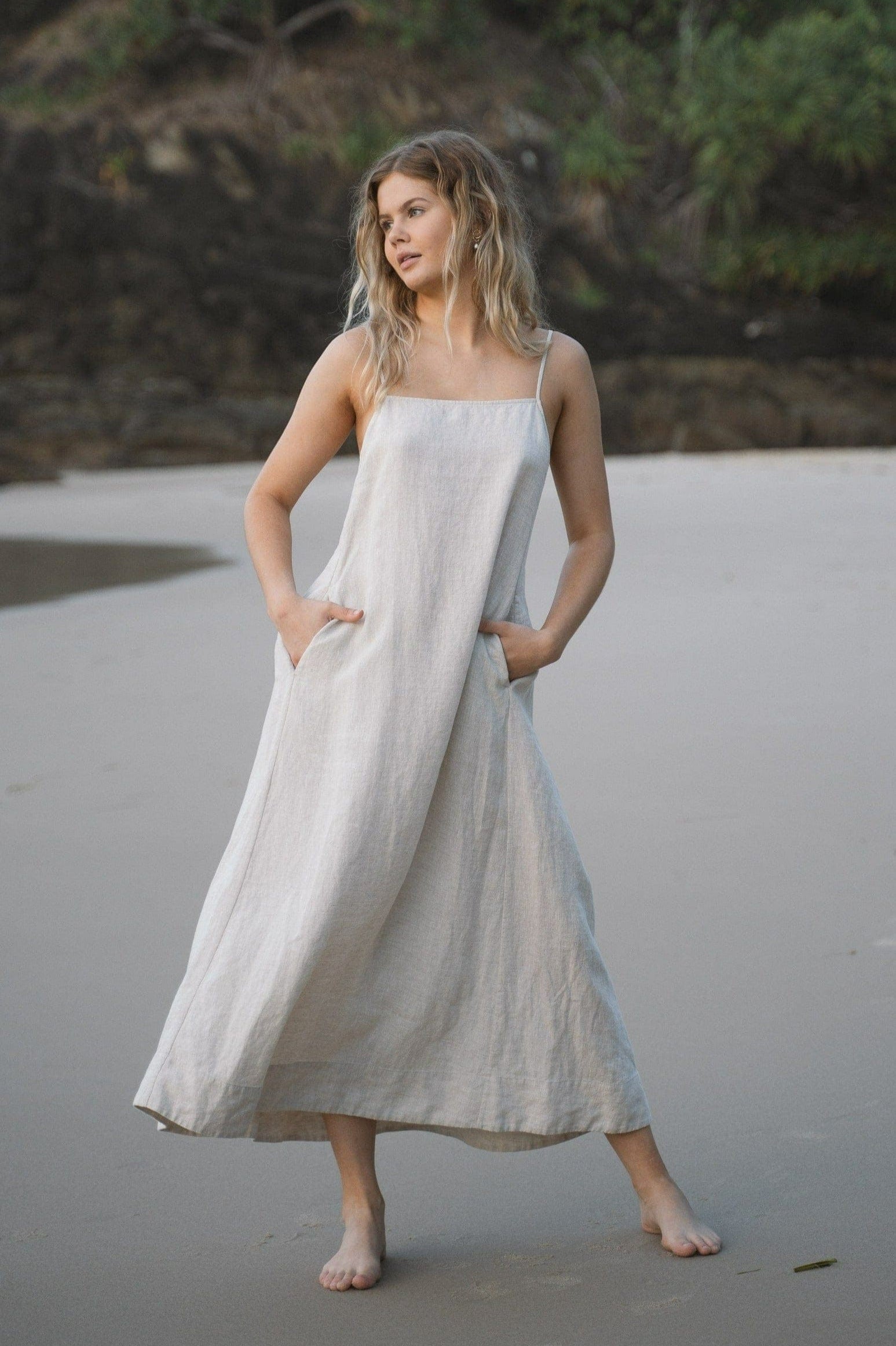 LILLY PILLY woman wearing a oatmeal Coco linen dress standing on a beach
