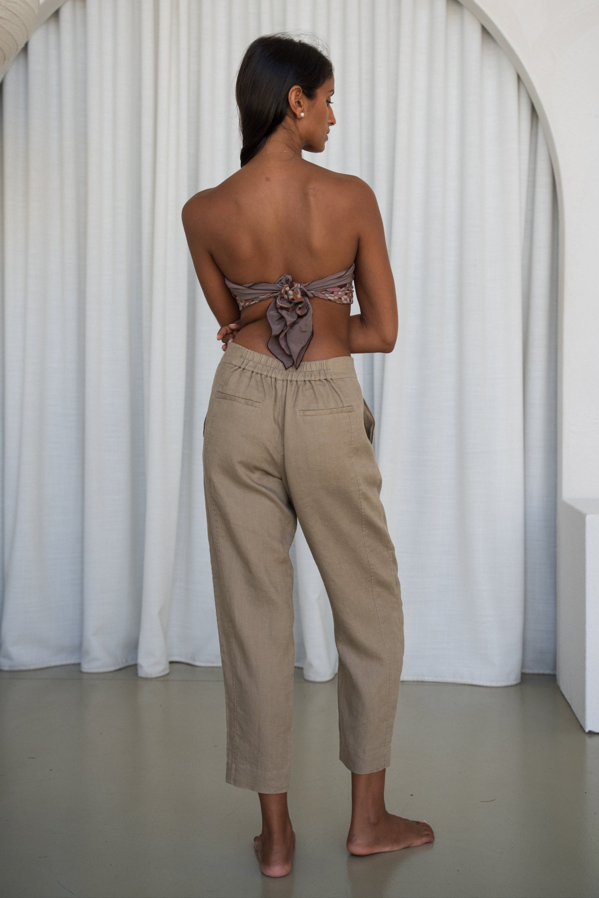 Woman wearing a strapless top and taupe Emer linen pants
