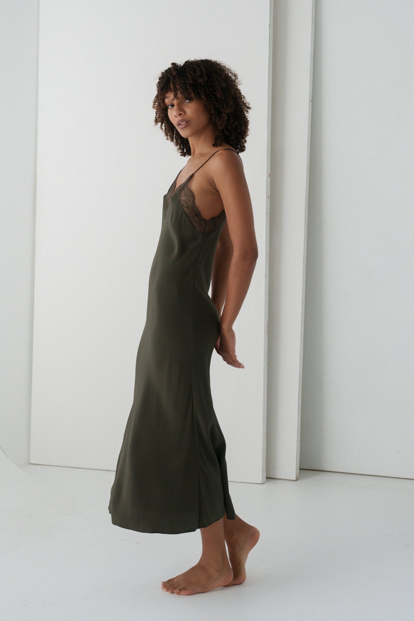 Woman wearing a khaki Freya silk slip dress against a white background
