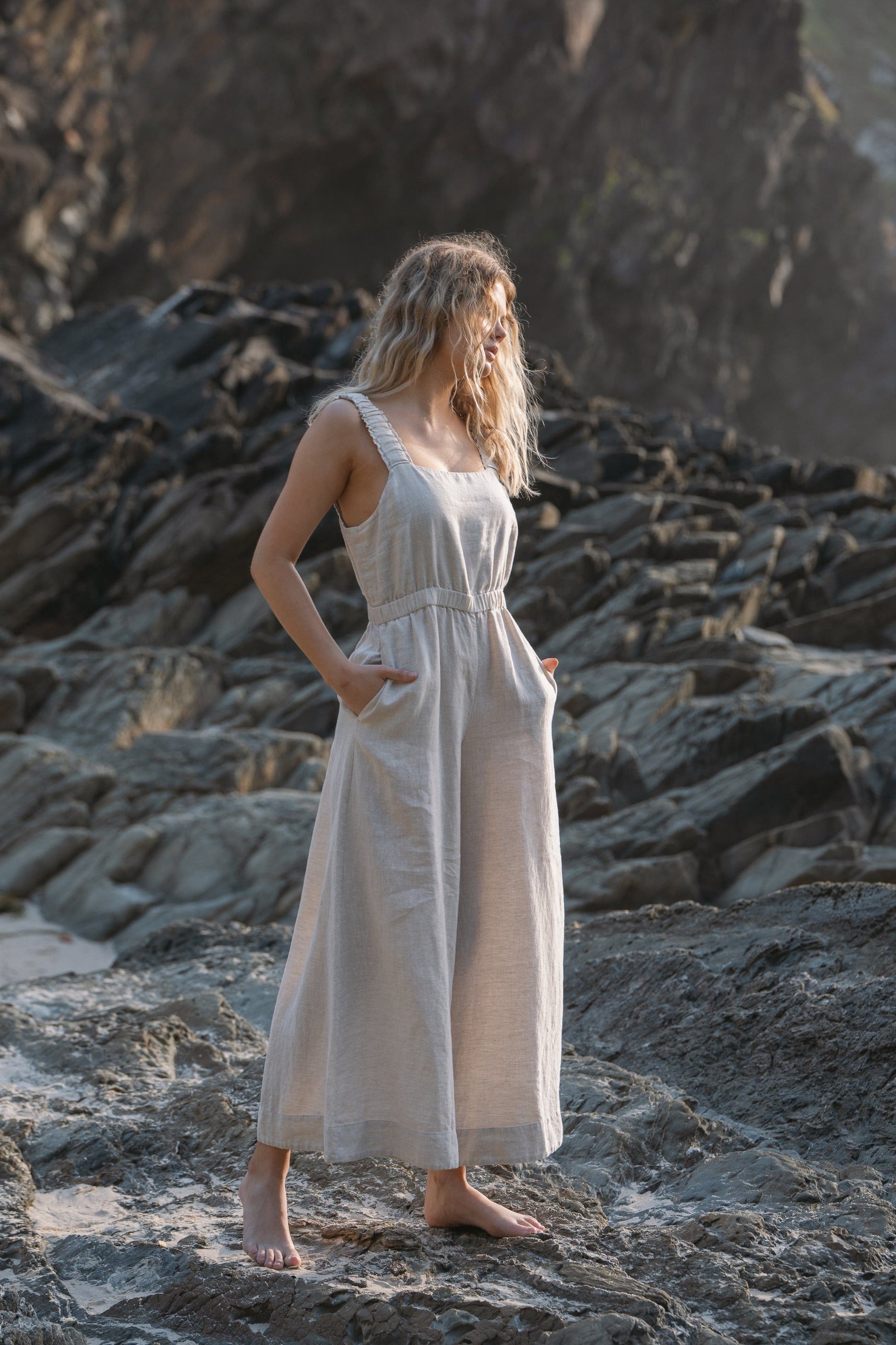 Lilly Pilly Collection European linen Keely jumpsuit in Oatmeal standing on rocks