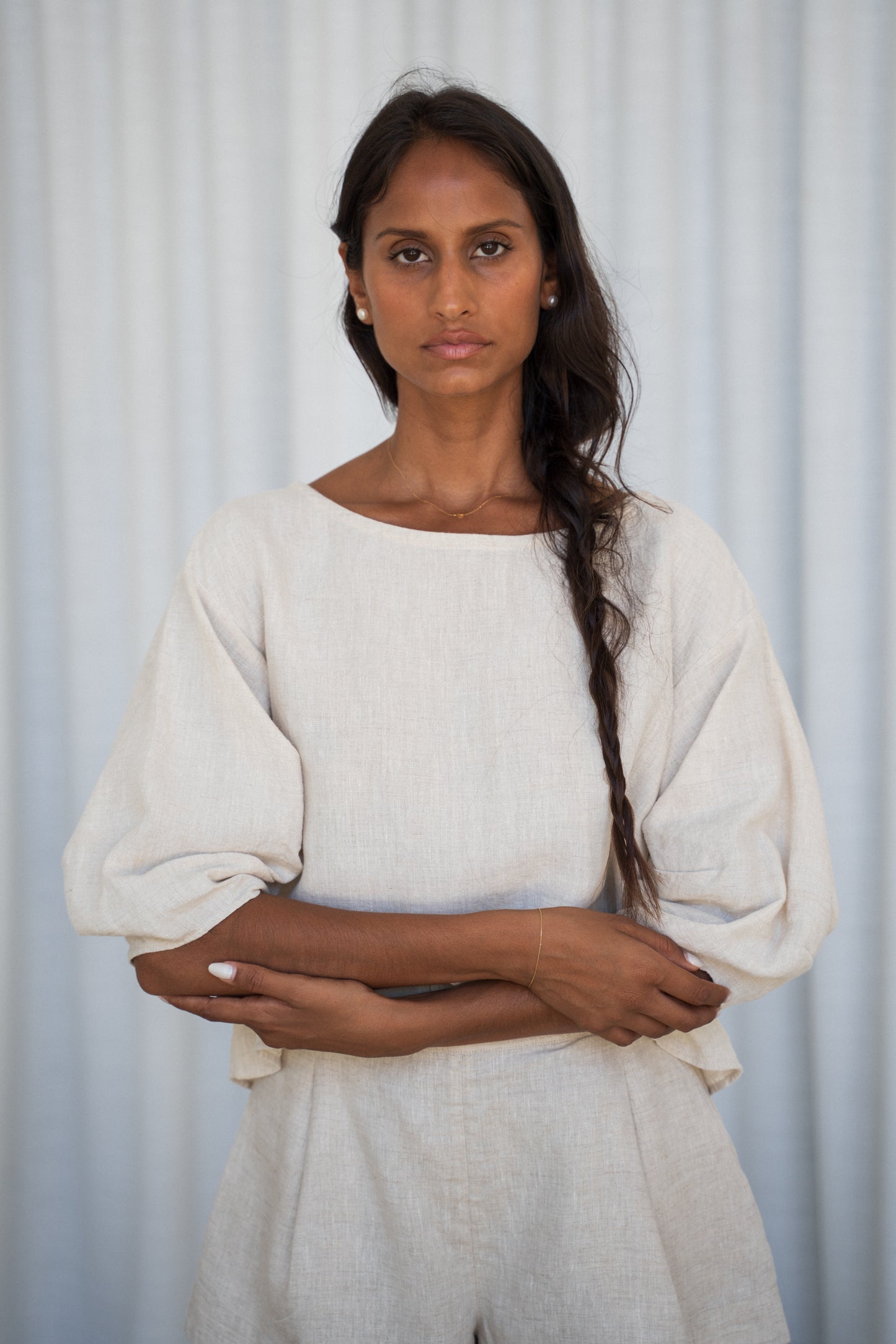Woman wearing a oatmeal Leia linen top against a light gray background
