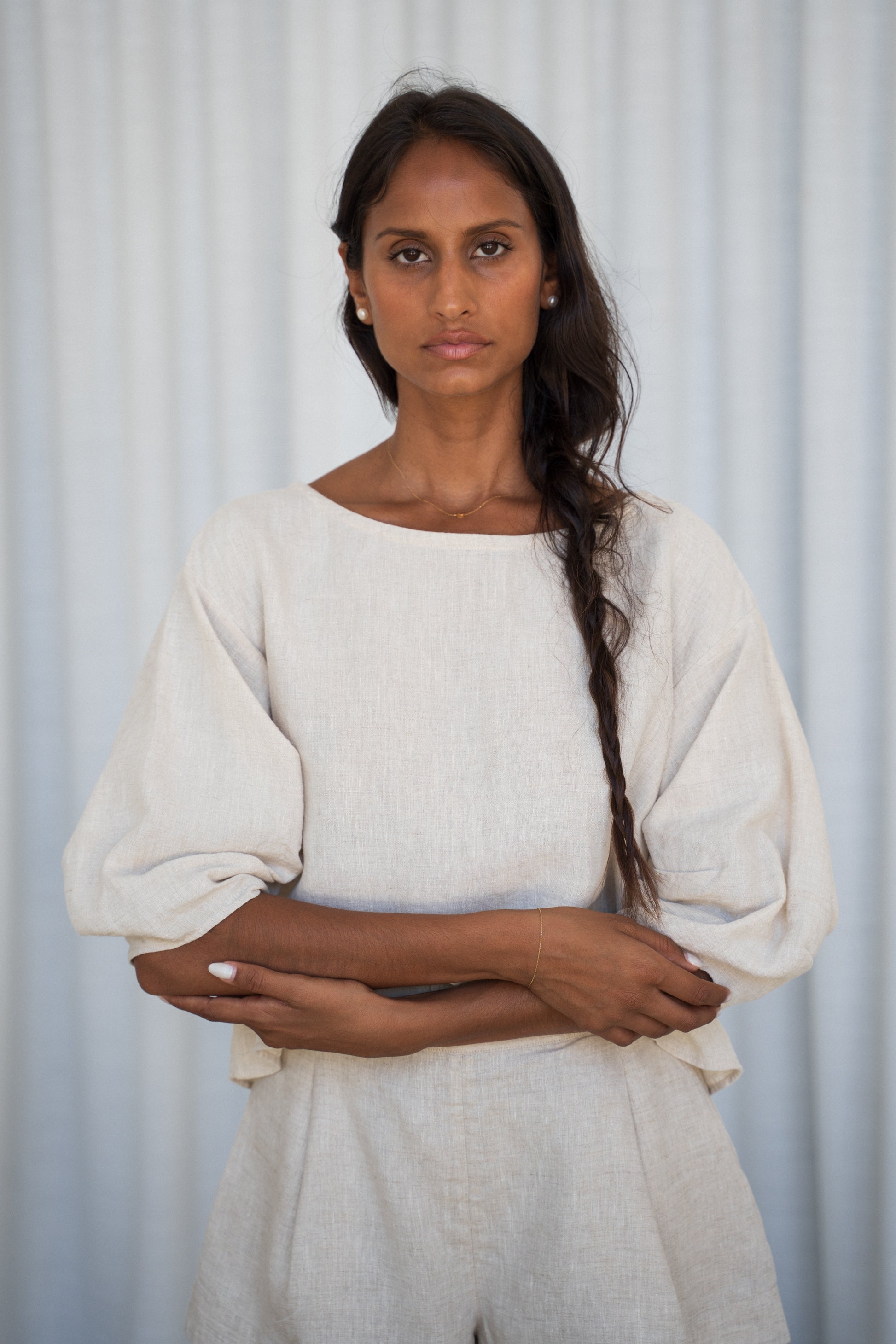 Woman wearing a oatmeal Leia linen top against a light gray background