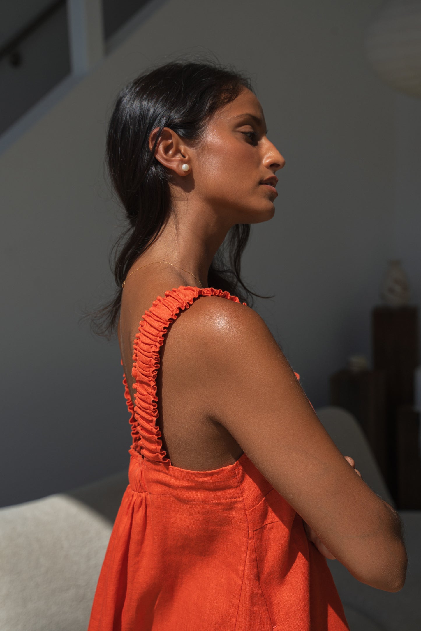 Close up side view of LILLY PILLY woman in an spritz Zahra linen dress showing back view while standing in front of a neutral background