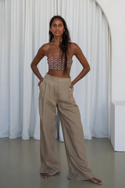 LILLY PILLY woman wearing Oli linen pants in Taupe with white curtain background